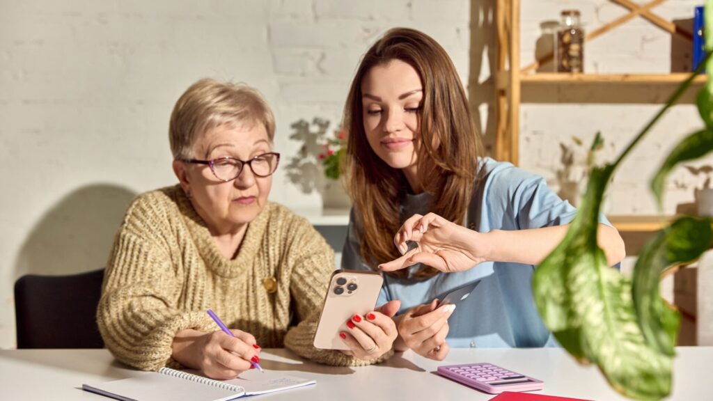 Eine jüngere Frau hilft einer Seniorin, ihren Pflegegrad überprüfen zu lassen.